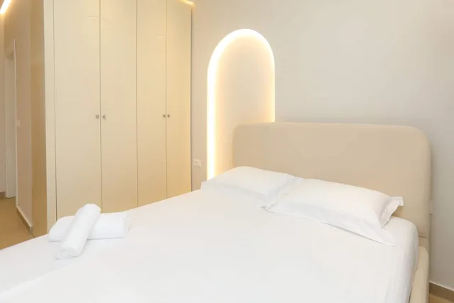 Doppelbett mit beleuchteter Bogennische hinter dem Kopfteil